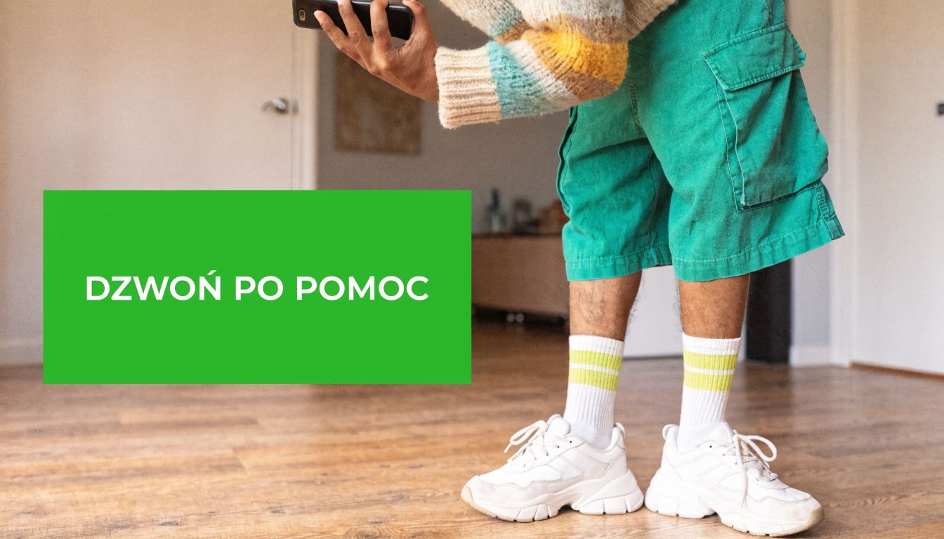 Osoba trzymająca smartfon w dłoniach, obok zielona plansza z napisem wzywającym do kontaktu po pomoc.